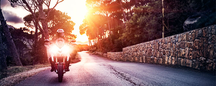 Man biking down a road at sunset